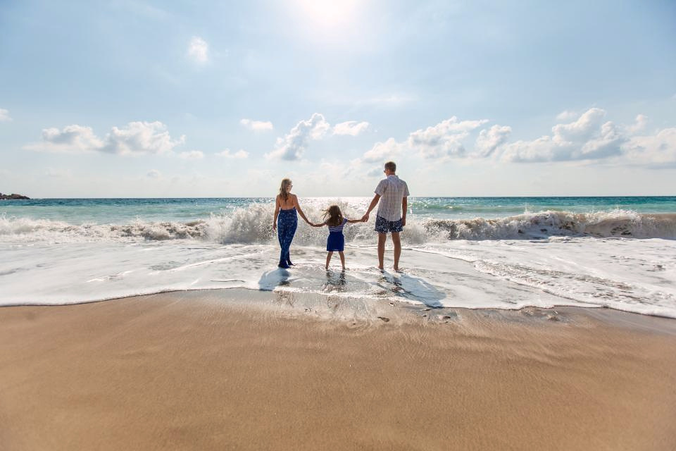 Familie som går hånd i hånd mot stranden i sol og varme